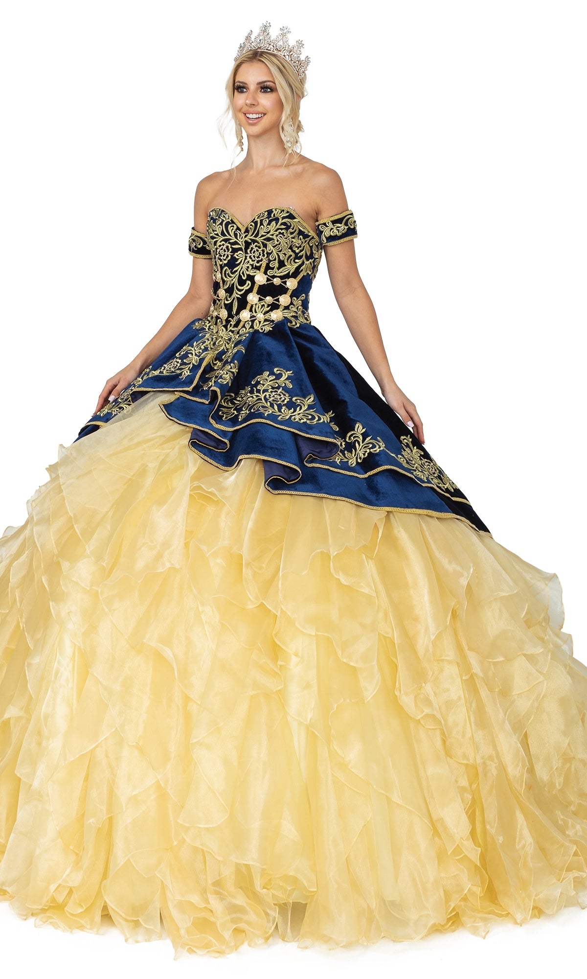 A woman poses in the Quinceanera Dress 1529 by Dancing Queen, featuring a jeweled crown, navy embroidered bodice, sweetheart strapless neckline, and layered yellow skirt—a modern take on a classic ball gown.